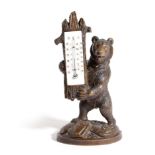 A BLACK FOREST LINDENWOOD BEAR THERMOMETER PROBABLY LATE 19TH CENTURY the standing bear holding