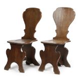 A NEAR PAIR OF GEORGE II OAK SGABELLO HALL CHAIRS MID-18TH CENTURY each with a dished seat (2)