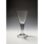 A large toasting glass or goblet c.1750, the generous drawn trumpet bowl rising from a thick plain