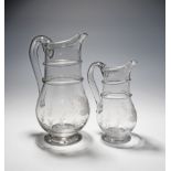 A graduated pair of glass jugs late 18th century, roughly engraved with a leaf and barley design