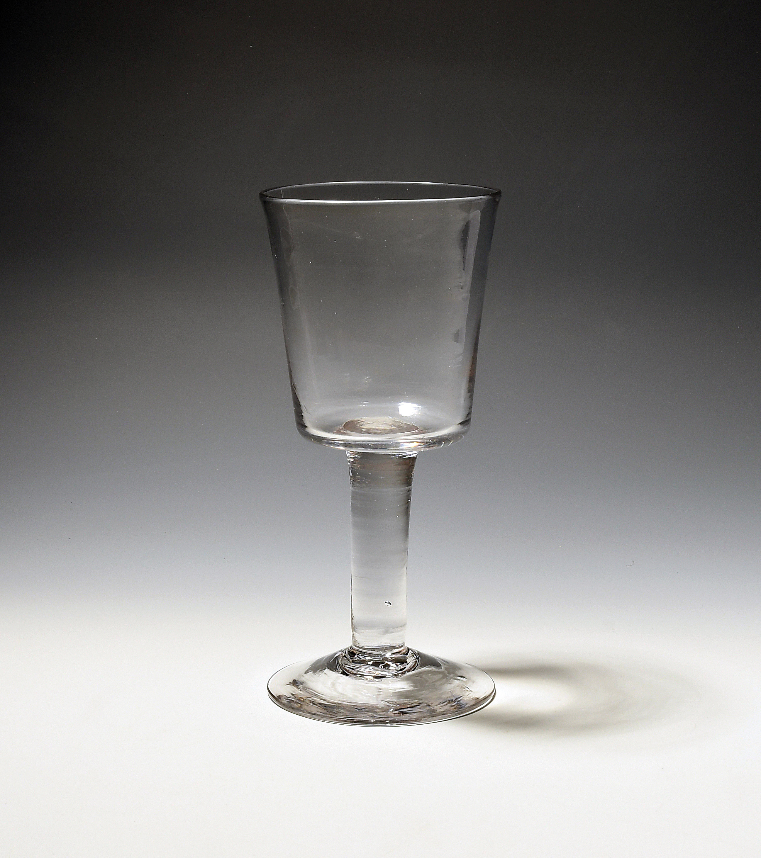 A glass goblet c.1750, the deep bucket bowl raised on a thick plain stem over a conical foot, 20.