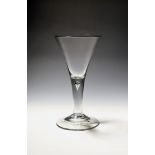 A large toasting glass or goblet c.1750, the generous drawn trumpet bowl rising from a thick plain