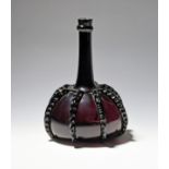 A Dutch amethyst glass decanter or bottle c.1760, the flattened globular body applied with rigaree