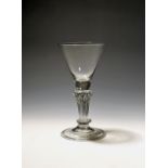 A wine glass c.1730, the funnel bowl rising from an eight-sided pedestal stem above a basal knop and