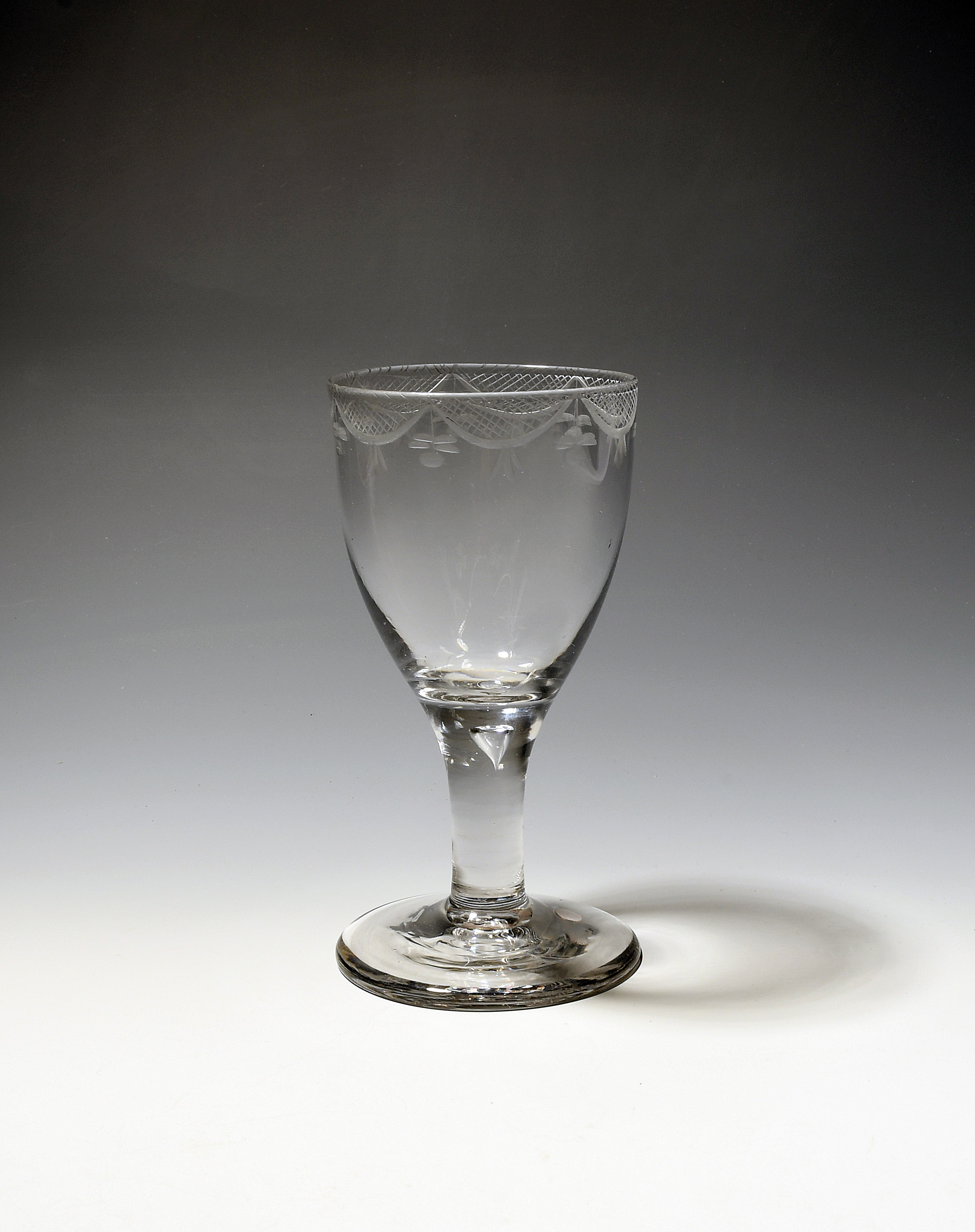 A large wine glass or goblet c.1750-60, the rounded funnel bowl engraved with a border of hatched