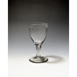 A large wine glass or goblet c.1750-60, the rounded funnel bowl engraved with a border of hatched