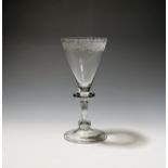 A wine glass c.1740, the funnel bowl engraved around the rim with a formal foliate border