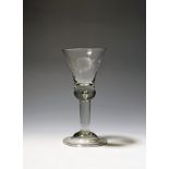 A wine glass c.1750, the bell bowl engraved with a stylized sunflower and a bird in flight, over a