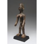 A Mossi standing female figure Burkino Faso with a crested coiffure and scarifications to the