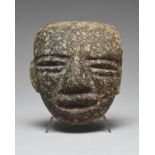 A Mexican mask probably Teotihuacan mottled black stone, with brows, recessed eyes and mouth, the