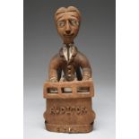 Thomas Ona. A Yoruba seated figure of an Auditor Nigeria on a chair and at a desk, the front