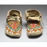 A pair of Sioux moccasins Plains hide, coloured glass beads and red cloth, 25cm long. (2)
