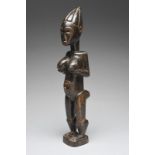 An Attie standing female figure Ivory Coast with a ribbed conical coiffure, supporting her breasts