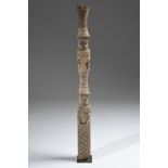 A Benin post carved with interlaced symbols, a kneeling female figure holding a game board and a