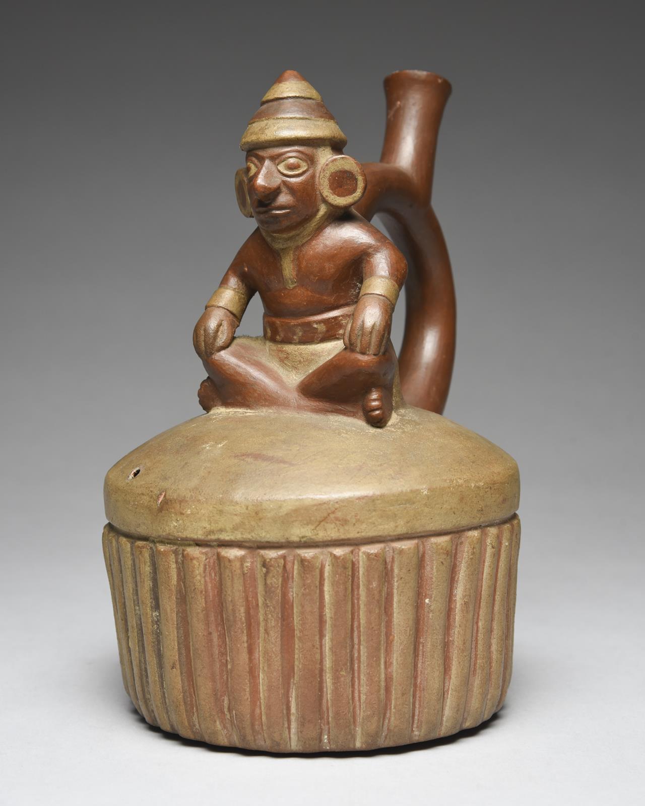 A Moche stirrup spout vessel Peru, circa 400 - 700 AD of circular ribbed form with a domed top