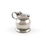 By Omar Ramsden, an Arts and Crafts silver mustard pot, London 1938, circular bellied form, spot-