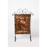A copper and patinated metal fire screen, the rectangular copper panel stamped in low relief with