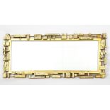 A Syroco gilt plastic wall mirror, rectangular, cast in low relief with brutalist design cast