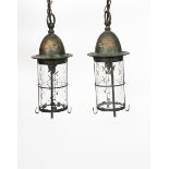 A pair of patinated metal and glass hall lanterns, each cylindrical form with domed top, the glass