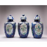 *A SET OF THREE CHINESE POWDER BLUE-GROUND FAMILLE VERTE EROTIC SUBJECT VASES AND COVERS KANGXI