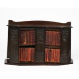 An Arts and Crafts wooden bookshelf, set with patinated metal plaques of Art Nouveau figures, with