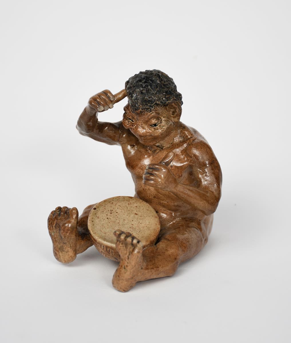 A Martin Brothers stoneware Imp Musician by Robert Wallace Martin, modelled seated playing a drum,