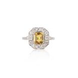 A yellow sapphire and diamond ring, of cluster design, set with a step-cut yellow sapphire