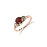 A garnet and diamond ring, collet-set with a circular mixed-cut garnet, the shoulders set with