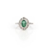 An emerald and diamond ring, collet-set with an oval emerald weighing 0.80 carats, within an open