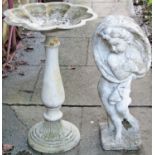 A reclaimed garden ornament in the form of a standing cherub on a tree stump grasping a cloak,