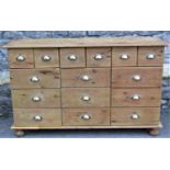 A stripped pine dresser fitted with an arrangement of fifteen drawers with vintage style cast