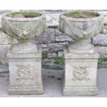 A pair of reclaimed garden urns of circular form with classical trailing swag detail and fluted