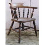 A 19th century beechwood smokers bow elbow chair with turned spindle back over a saddle shaped