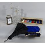 Three glass decanters, a tortoiseshell cased manicure box, folding black parasol, carriage clock and