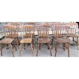 A harlequin set of ten stained elm and ashwood Windsor stick back kitchen chairs with splayed ring