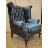 A reproduction Georgian style blue leather upholstered wing armchair with shaped outline, deep