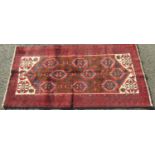 Unusual Meshed old Belouchi rug with geometric panel decoration upon a rich red ground, 200 x 100cm