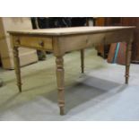 A Victorian stripped pine kitchen table of rectangular form fitted with a frieze drawer, raised on