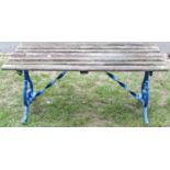 A low garden table with open weathered slatted top, raised on painted cast alloy scrolled