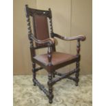 An Edwardian oak elbow chair in a Carolean manner with carved detail and upholstered seat and back