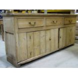 An antique rustic stripped pine kitchen dresser base, enclosed by a pair of tongue and groove