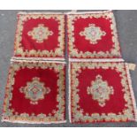 Four identical Persian Kirman mats with central medallion decoration upon a red ground, each 60 x