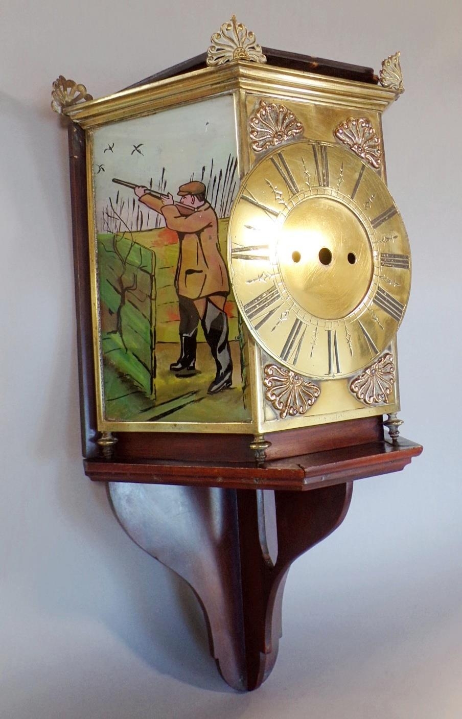 Unusual clock case with brass dial, flanked by coloured glass panels showing sportsmen, with