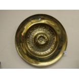 A 19th century brass arms dish with embossed detail with Latin script, to the centre rearing lion,