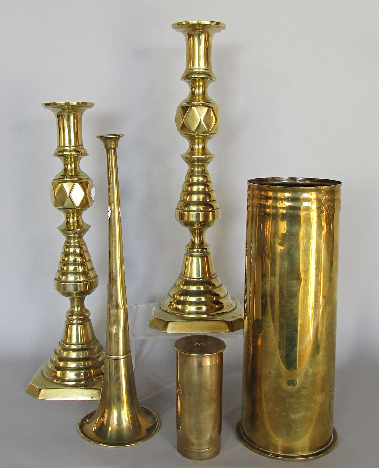 Brassware: a pair of turned brass candlesticks, shell casing, three coaching horns by Alfred May,