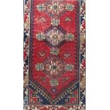 Good Turkish rug with medallion decoration in relief upon a red ground with blue running borders,