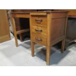 A stripped oak kneehole single pedestal desk fitted with three long drawers with brushing slide