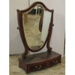 An Edwardian mahogany shield shaped toilet mirror with bevelled edge plate raised on a bow fronted