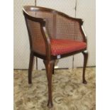 An Edwardian bergere chair with shaped outline, loose upholstered seat cushion, cabriole forelegs (