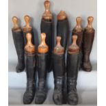 Five pairs of vintage black leather riding boots with vintage wooden boot trees